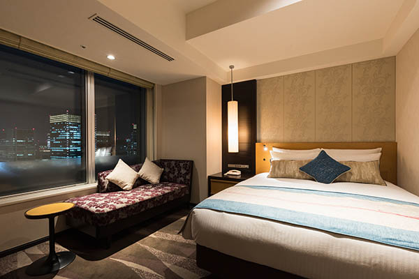 QUEEN DELUXE 20sqm room with bed, desk and sofa including a view of outside at night