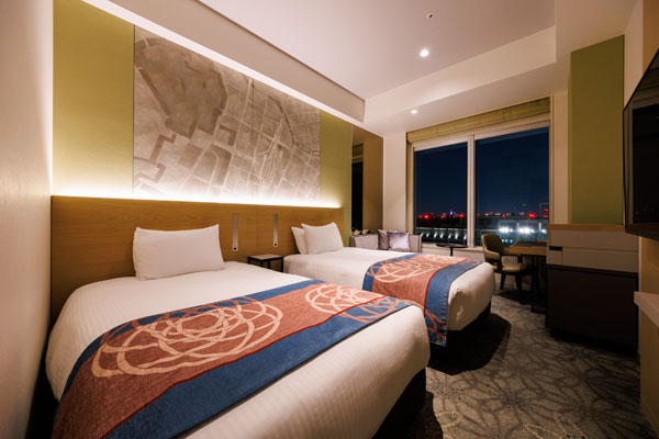 TWIN 25sqm room with 2 beds, desk and chairs including a view of outside at night