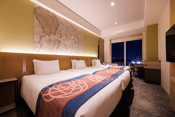 TRIPLE 25sqm room with 3 beds, desk, chair and stool at night